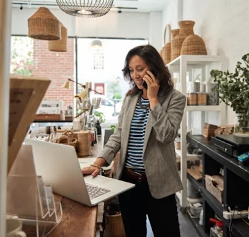 woman on phone in front of laptop at small business