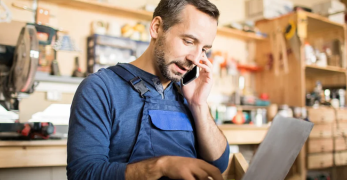 small businessman speaking on smartphone in front of laptop