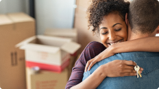 Smiling couple hugging while holding new purchase keys in hand
