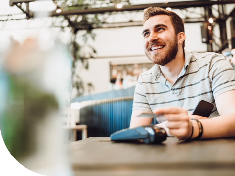 Man smiling while out to dinner paying with debit card