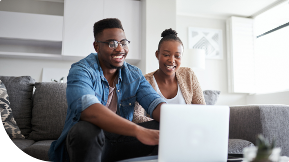 man and woman sitting on couch looking at a laptop