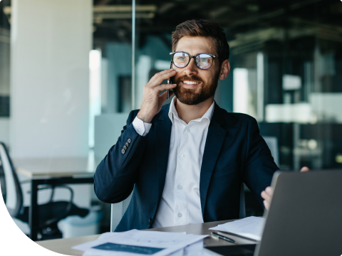 man in office sitting at desk on cell phone