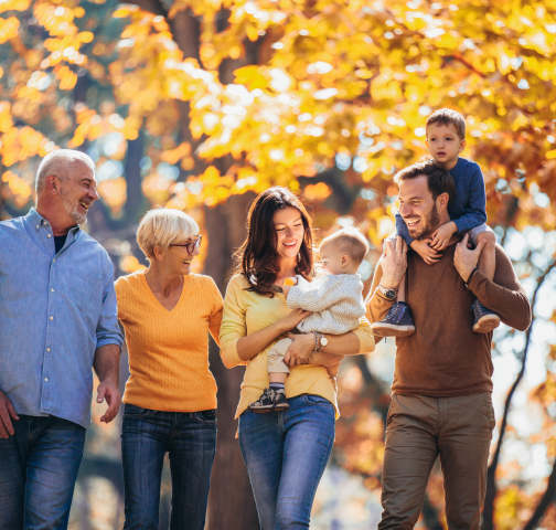 3 generations of a family walking in fall leaves