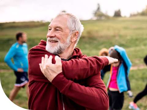 Older man looking off into distance at a workout class smiling