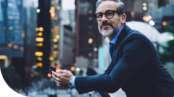 businessman looking out over the city holding smart phone