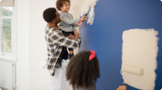 father and two children painting a wall 