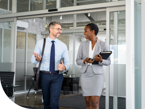 two businesspeople walking out of place of employment smiling