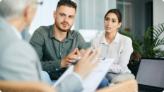 man and woman sitting on couch talking to a financial advisor