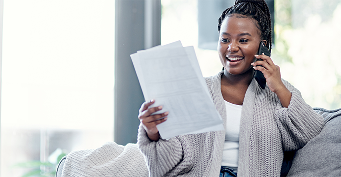 Woman talking on smartphone while looking at banking statements