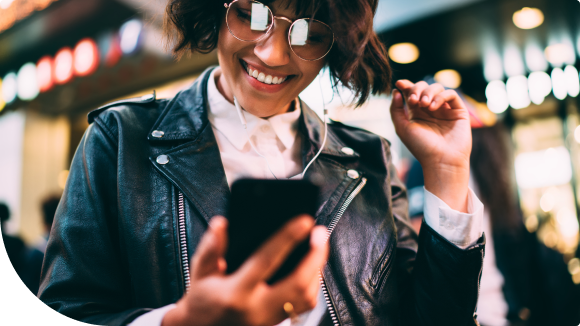 woman with glasses looking at her phone outside