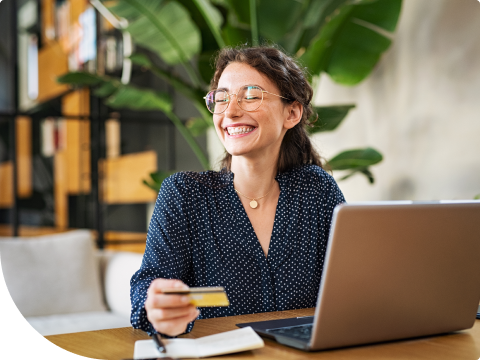 person smiling with a card at a laptop