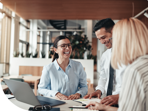 two women and a man at a desk with laptop in office