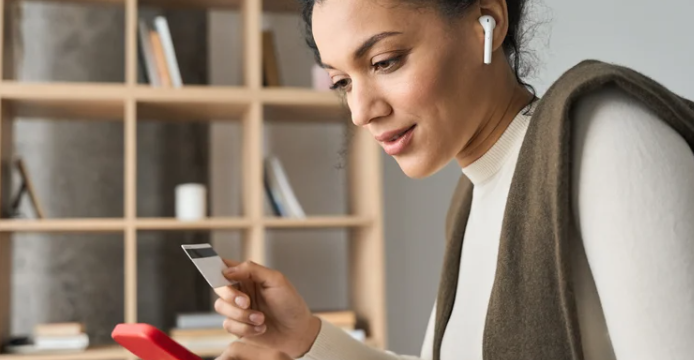 woman holding credit card and talking on ear buds