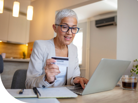 older woman logging into online banking holding her debit card
