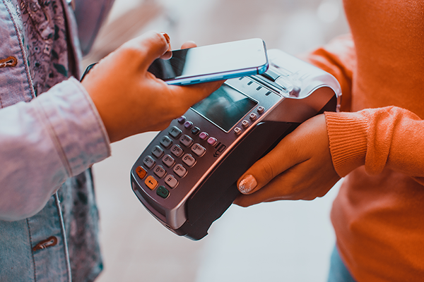 person paying for item from phone onto a payment POS terminal