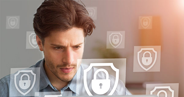 Man looking intently into computer with security symbols all around