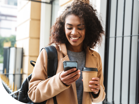 young person with a phone and a to go coffee