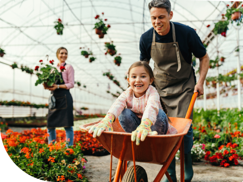 Person pushing child in a wheel barrow in garden center