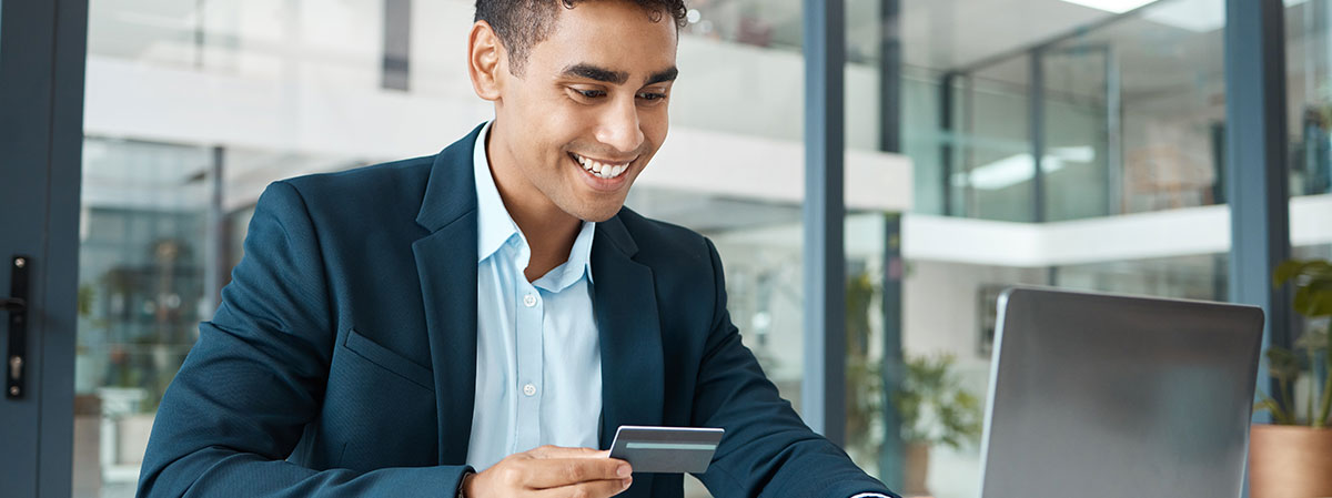 young businessman logging into online banking while looking at credit card