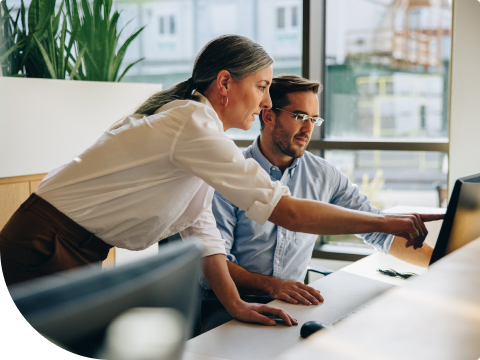 businesswoman looking over colleagues shoulder at computer screen