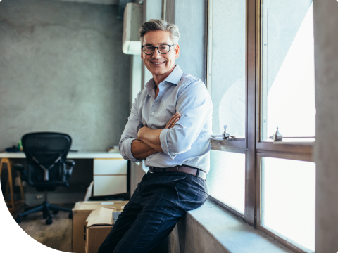 Businessman smiling and sitting on commercial real estate window