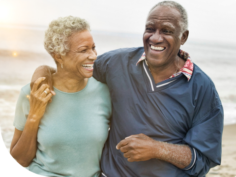 older couple smiling while walking on the beach